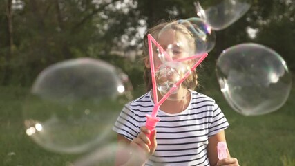 cute little girl blowing soap bubbles. carefree happy kid is playing in the park. kid funni play emo