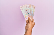 Hispanic Hand Holding 10 Colombian Pesos  Banknotes Over Isolated Pink Background.