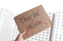 A Man Holds A Cardboard Poster With Charlie Hebdo Crossed Out