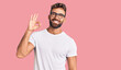 Young hispanic man wearing casual clothes and glasses smiling positive doing ok sign with hand and fingers. successful expression.