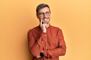 Wall Mural - Handsome caucasian man wearing casual clothes and glasses smiling looking confident at the camera with crossed arms and hand on chin. thinking positive.