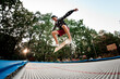 view young guy actively jumping with skateboard on trampoline