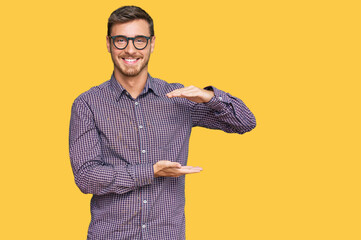 Handsome caucasian man wearing casual clothes and glasses gesturing with hands showing big and large size sign, measure symbol. smiling looking at the camera. measuring concept.