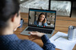 © fizkes - Rear back view young indian ethnicity female teacher giving online educational class to millennial female client in headphones, using video call laptop application, distant communication concept.