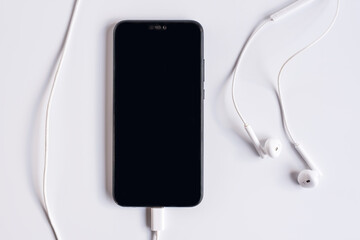 Smartphone with earphones on white background. Close-up of smart phone with headphones on a white background. Listen to music