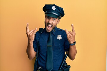 Sticker - Handsome hispanic man wearing police uniform shouting with crazy expression doing rock symbol with hands up. music star. heavy music concept.