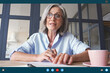 © insta_photos - Senior older middle aged business woman teacher, remote tutor, distance coach talking to camera at virtual meeting web conference video call chat working online. Videocall app screen web cam view.