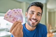 Young Handsome Man Smiling Happy Holding Mexican Pesos Banknotes At Home