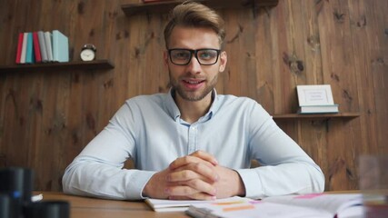 Wall Mural - Young business man, remote teacher, professional distance coach talking to camera sitting at office desk conference video calling, giving webinar, online class, teaching or streaming, webcam view.