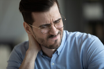 Businessman touch nape feeling pain in neck suffers from sudden ache, massaging tensed neck muscles to reduce discomfort, close up. Long hours computer work, sedentary lifestyle, pinched nerve concept