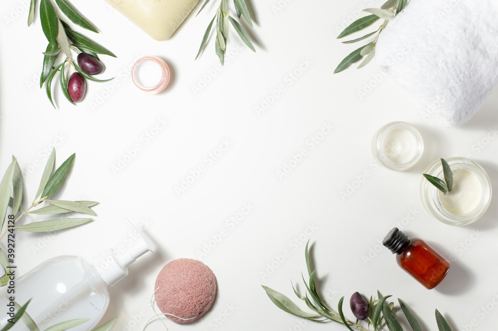 Spa and beauty. A set of cosmetics for care. Soap, cream, towel, shampoo, sponge and olive tree sprigs are arranged around the perimeter on a white background. - obrazy, fototapety, plakaty 