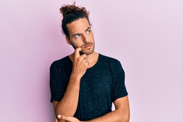 Wall Mural - Young handsome man with long hair wearing casual clothes serious face thinking about question with hand on chin, thoughtful about confusing idea