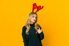 Young Blonde Caucasian Woman Wearing Reindeer Horns Pointing With Finger At You As If Inviting Come Closer.