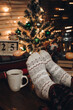 © Юлія Мартинюк - Feet in Christmas socks. Close up on feet. Winter and Christmas holidays concept. The cup of hot drink. Cozy scene. Background with christmas decor. Christmas background.