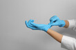 © New Africa - Doctor putting on medical gloves against light grey background, closeup. Space for text