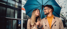 Young Couple In Love Standing In The Rain Under An Umbrella