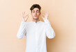 © Asier - Young caucasian man isolated on beige background relaxes after hard working day, she is performing yoga.