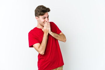 Wall Mural - Young caucasian man isolated on white background laughing about something, covering mouth with hands.