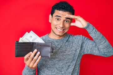 Sticker - Young handsome hispanic man holding wallet with dollars stressed and frustrated with hand on head, surprised and angry face