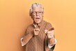 © Krakenimages.com - Senior grey-haired woman wearing casual clothes and glasses pointing fingers to camera with happy and funny face. good energy and vibes.