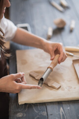 Female potters hand making clay pottery at the table with a different wooden tools close up.