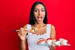 © Krakenimages.com - Young brunette woman eating omelet sushi using chopsticks celebrating crazy and amazed for success with open eyes screaming excited.