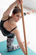 Young Attractive woman Doing Stretching Exercise With Wooden Exercise Stick At Pilates Studio