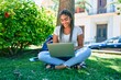 © Krakenimages.com - Young african american student woman smiling happy using computer laptop sitting on the grass at the university campus