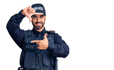  Young hispanic man wearing police uniform smiling making frame with hands and fingers with happy face. creativity and photography concept.