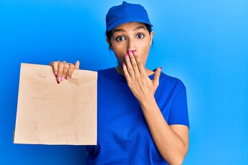 Sticker - Beautiful brunette woman holding take away paper bag covering mouth with hand, shocked and afraid for mistake. surprised expression