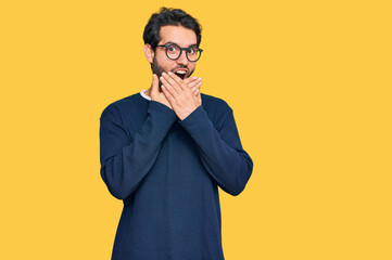 Canvas Print - Young hispanic man wearing casual clothes and glasses shocked covering mouth with hands for mistake. secret concept.