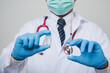 © Chanakon - Close Up Asian bald Doctor in white coat, stethoscope, blue glove holding a.bottle of vaccine and syringe isolated on white background.