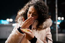 Young Woman In Winter Jacket Coughing Outdoors And Holding Medicine , Or Throat Lozeng