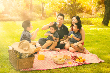 Wall Mural - Happy parents playing and picnicking with their kids