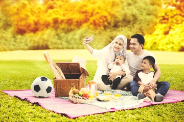 Wall Mural - Muslim family take selfie while picnicking at autumn