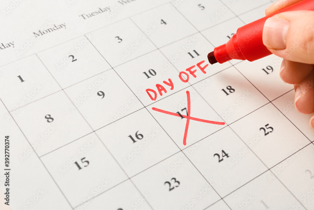 Woman marking day off in calendar, closeup