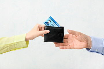 Poster - Male and female hands with driving license in wallet on light background