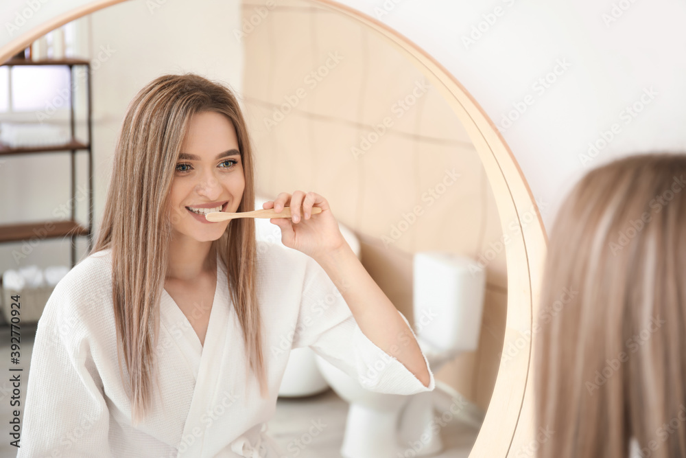 Young woman brushing teeth in bathroom