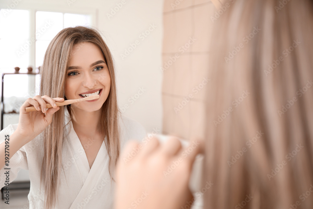 Young woman brushing teeth in bathroom