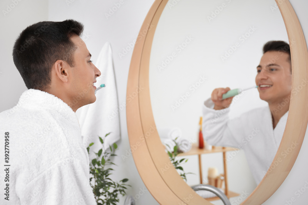 Young man brushing teeth in bathroom