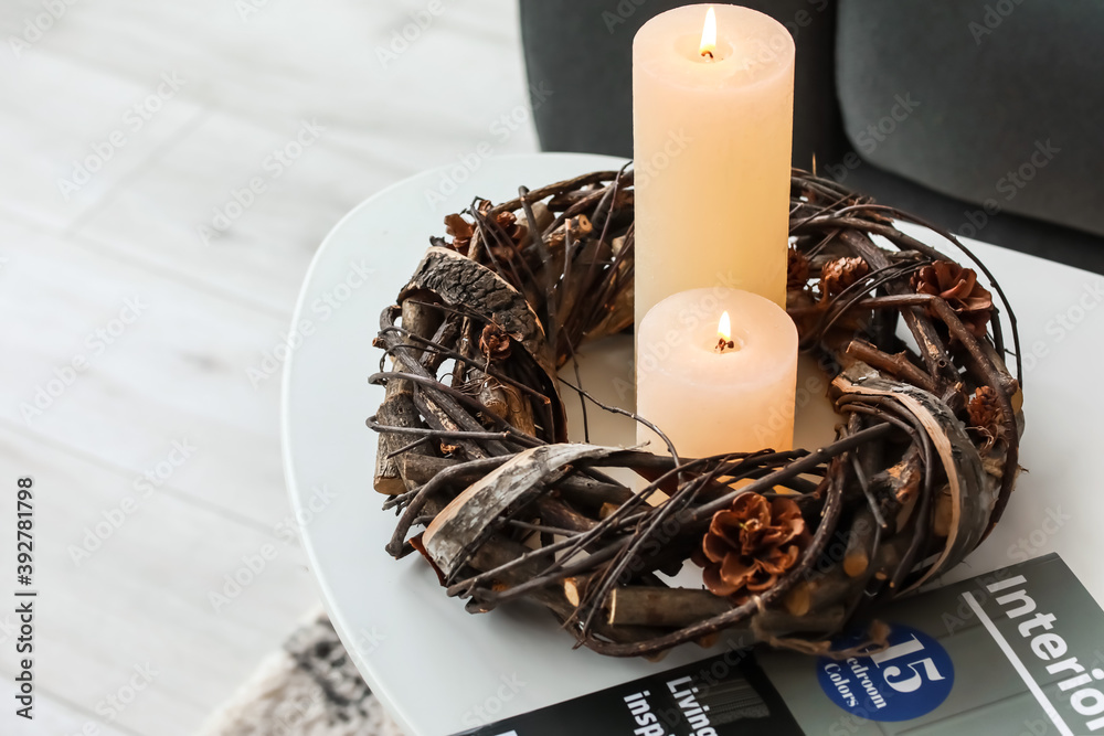 Burning candles and magazine on table in room