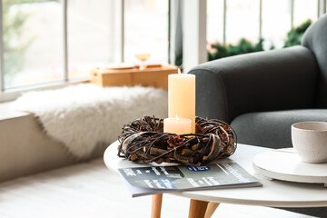 Burning candles and magazine on table in room