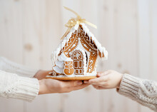 Adult And Child Are Holding Gingerbread House.
