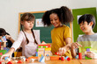 © twinsterphoto - Group of multiethnic school friends using toy blocks in classroom, education, learning, teamwork. Children playing with wooden blocks in classroom