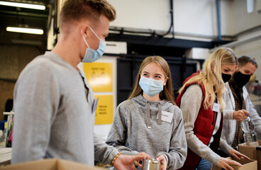 Group of volunteers in community charity donation center, food bank and coronavirus concept.