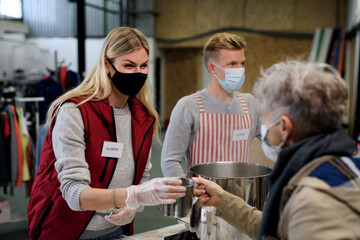 Volunteers serving hot soup for homeless in community charity donation center, coronavirus concept.