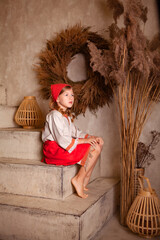 Wall Mural - little girl in a light linen shirt and a red scarf in a rustic style