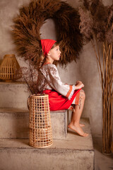 Wall Mural - little girl in a light linen shirt and a red scarf in a rustic style