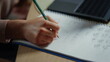 © stockbusters - Student hand writing in notebook indoors. Unknown girl doing homework inside.