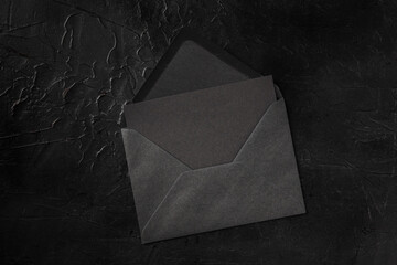 Wall Mural - A black card in a black envelope mockup, shot from the top on a black background with a place for text